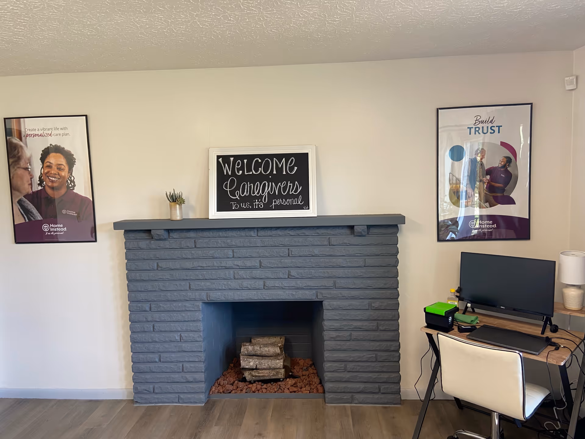 Interior reception area with a blue-gray brick fireplace, welcome sign, and desk.