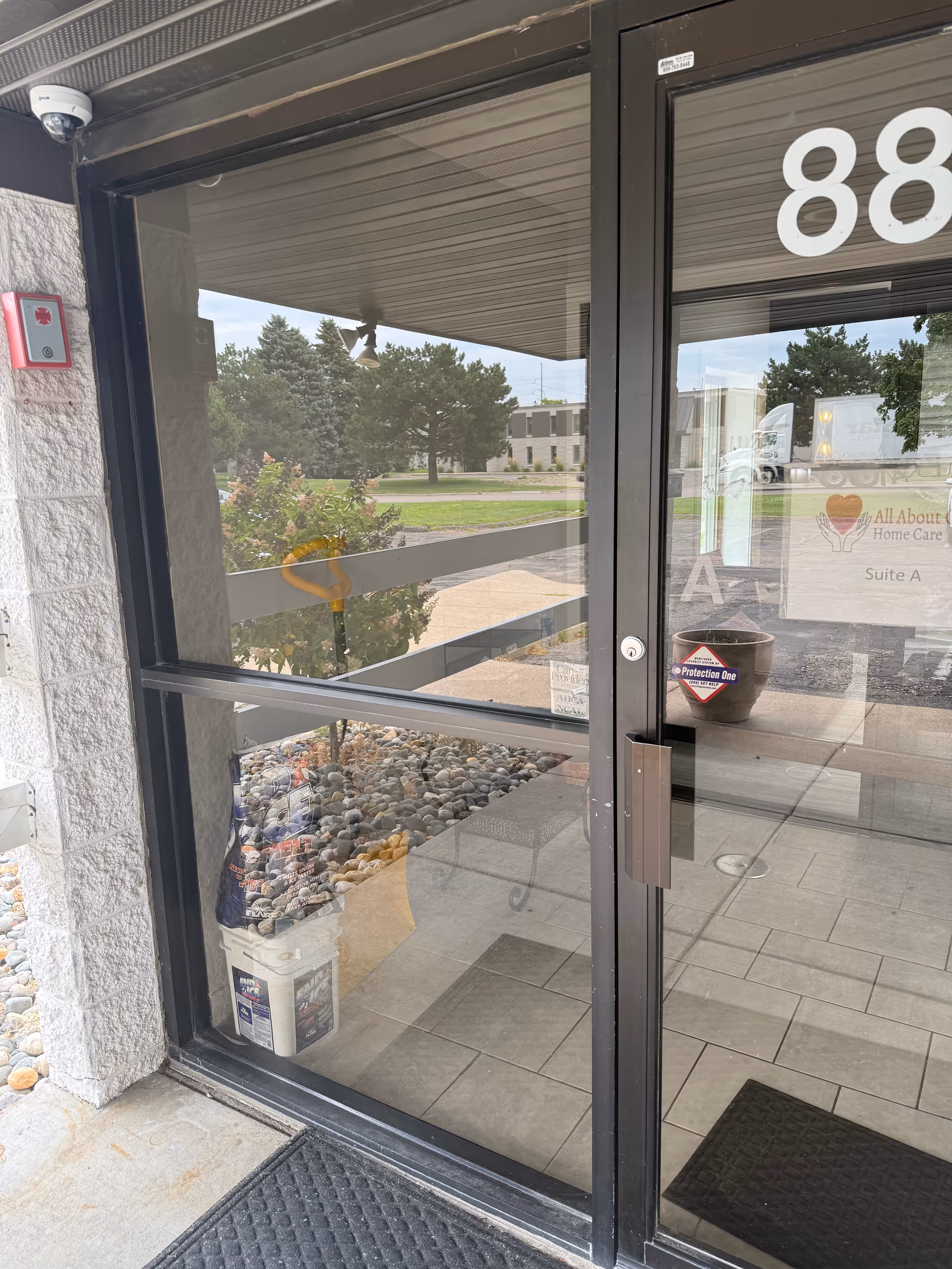 Glass front entrance door with number 88, exterior view of rocks and plants outside.