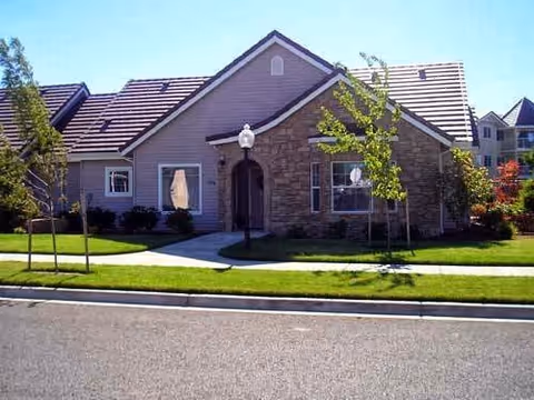 Single-story building exterior with stone accents, manicured lawn, and a walkway to the entrance.