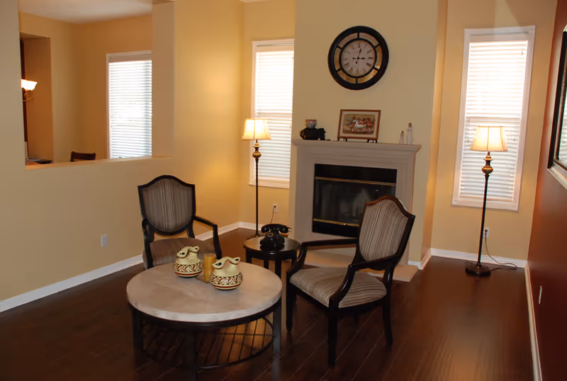 Cozy living room with two striped armchairs, round coffee table, fireplace, and lamps.