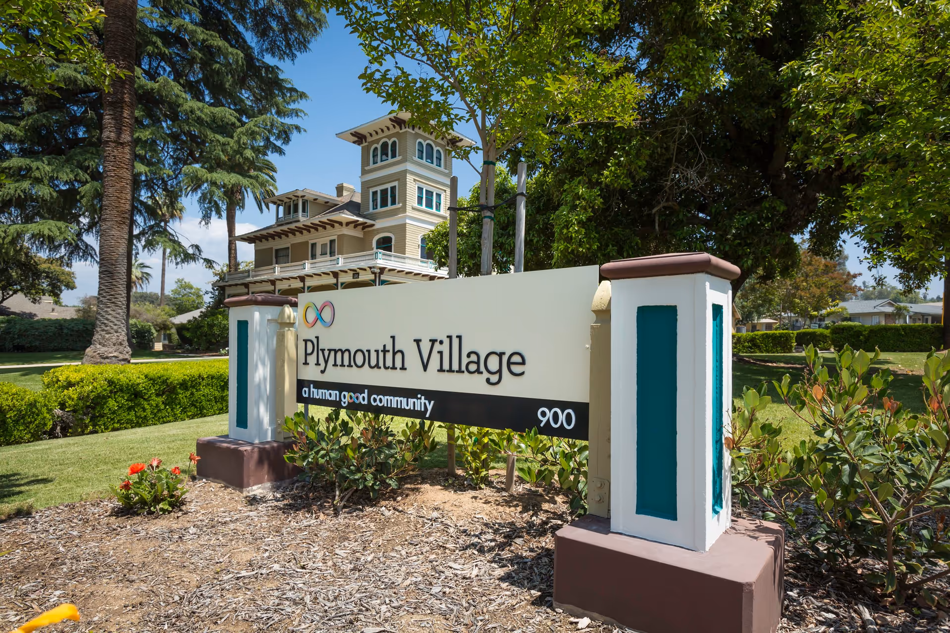 Plymouth Village sign with facility building and landscaping in background
