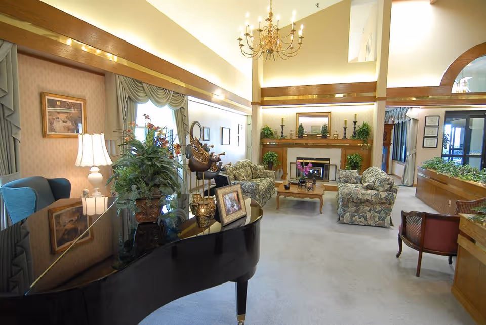 Elegant senior living lobby with piano, fireplace, seating, and potted plants.