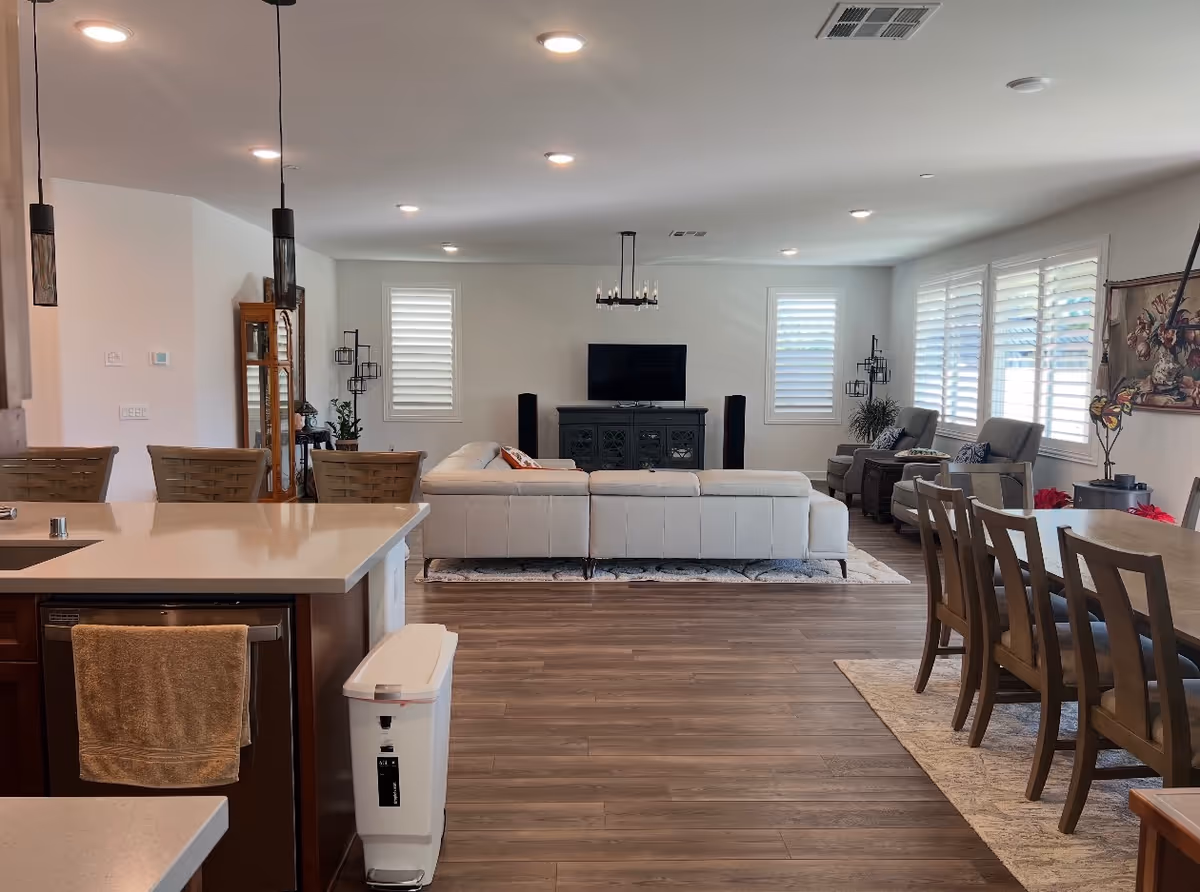 Open concept living area with white sectional sofa, TV, dining table, and kitchen island.