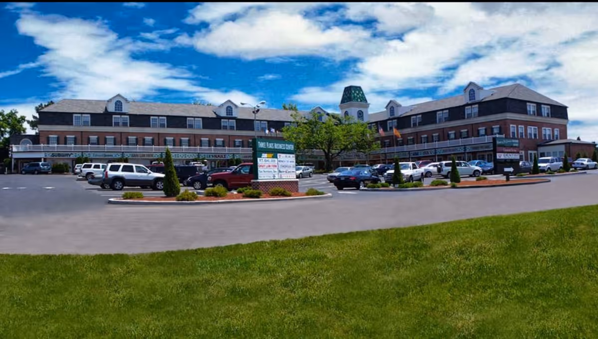 Exterior view of a senior living facility with a parking lot and well-kept lawn.