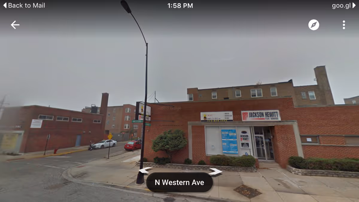 Brick storefront building on a city street with sidewalks, signs, and a front entrance.