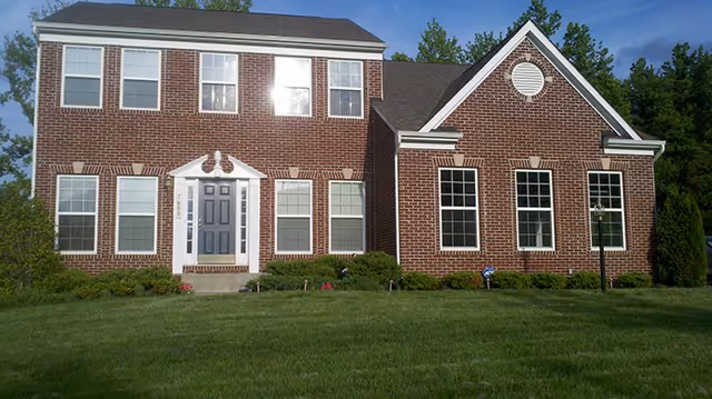 Brick two-story assisted living building with a central front door and green lawn.