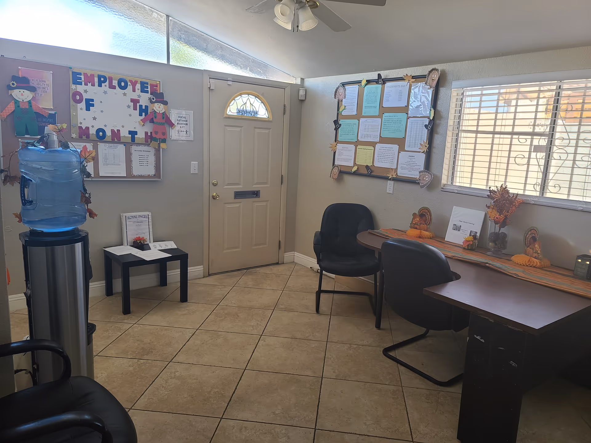 Interior of a senior care facility reception area with a water cooler, bulletin boards, and chairs.