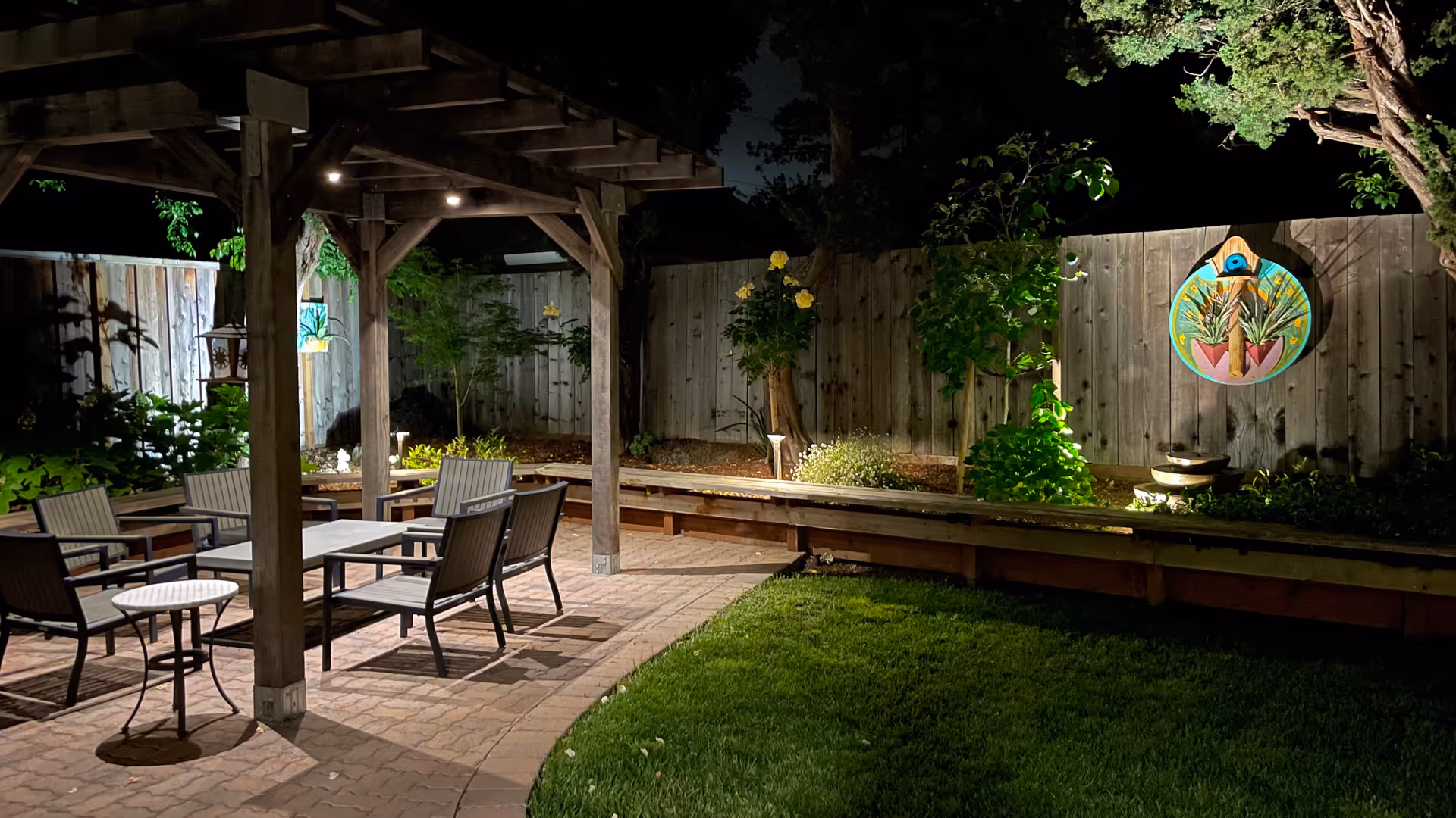 Night view of an outdoor patio with seating under a wooden pergola.
