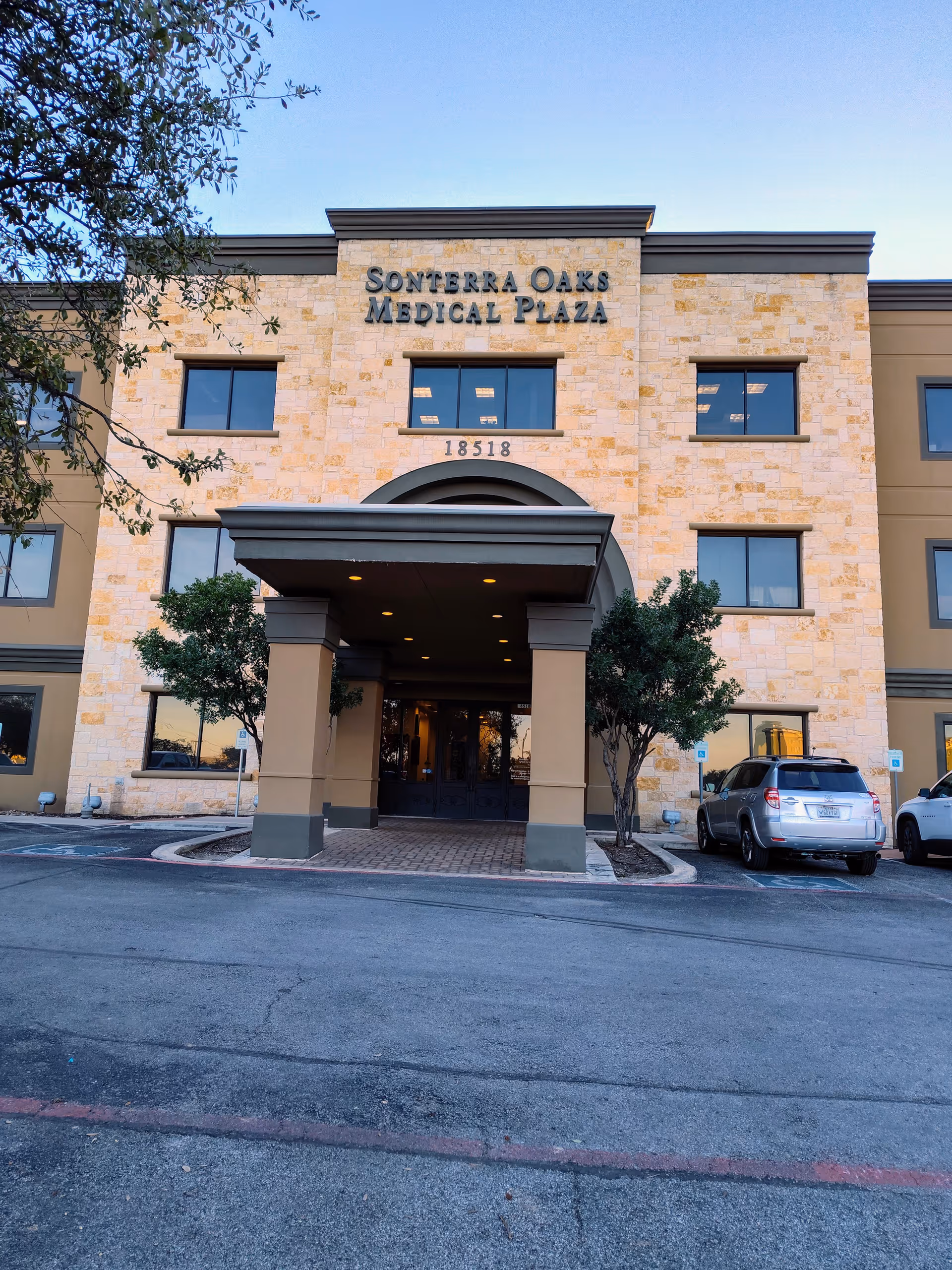 Exterior view of a medical plaza entrance with stone facade and covered porte-cochère.