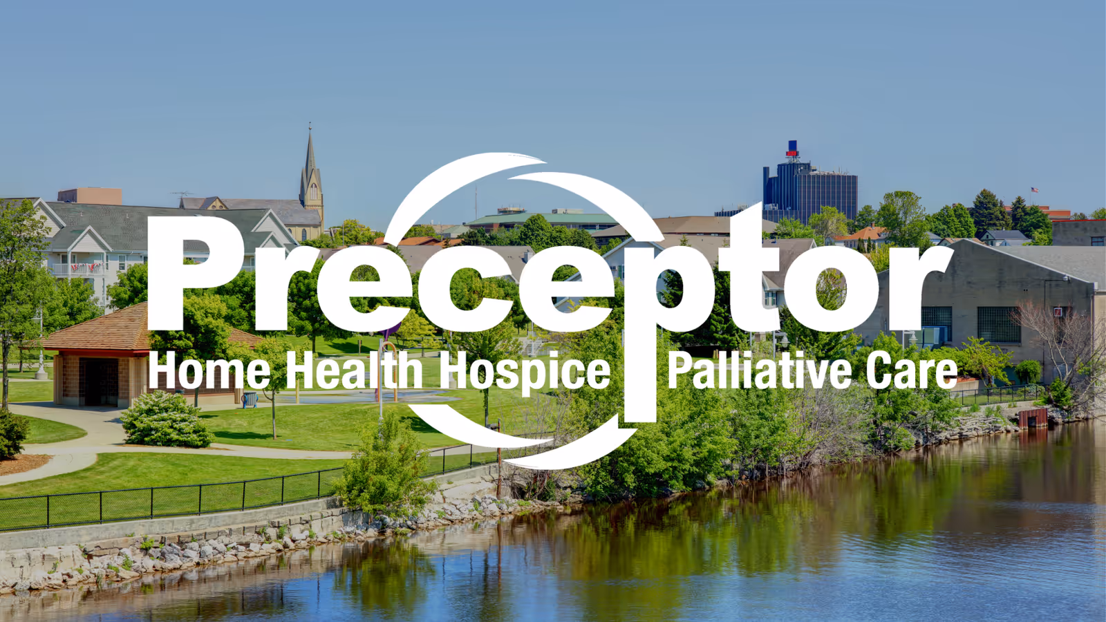Exterior view of Preceptor facility by a river with trees and campus buildings.