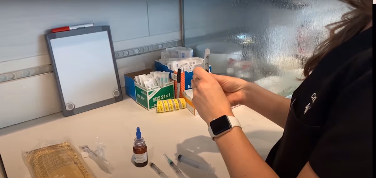 Caregiver prepares IV supplies on a clinical counter with syringes and boxes.