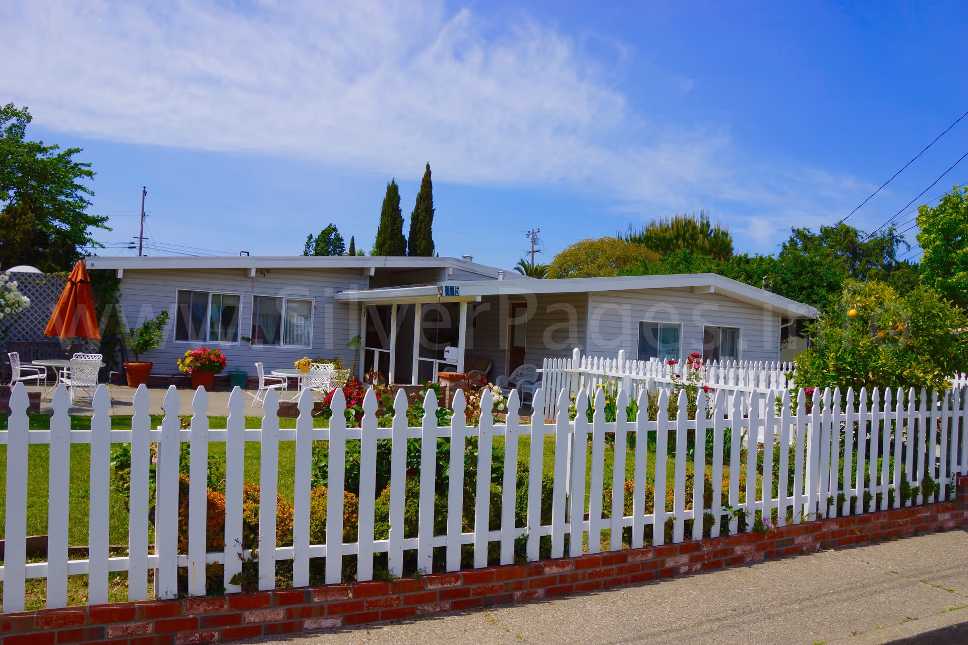 Single-story senior living facility with white picket fence and outdoor seating.