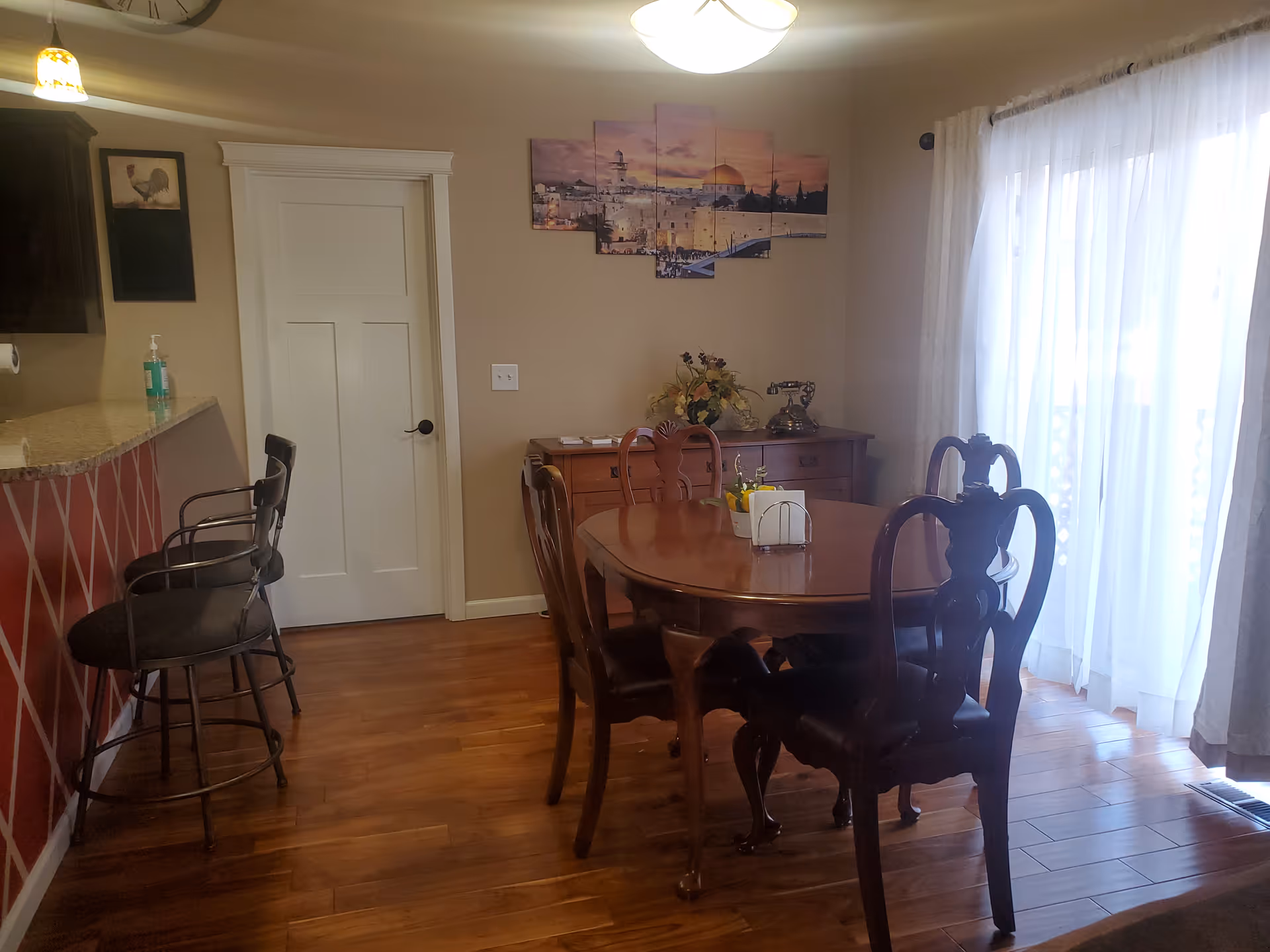 Cozy dining room with round wooden table, chairs, bar seating, and sliding glass doors.