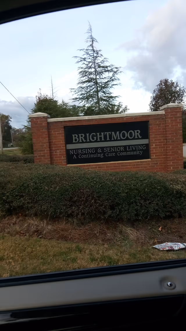 Red brick entrance sign reading Brightmoor Nursing & Senior Living with shrubs nearby.