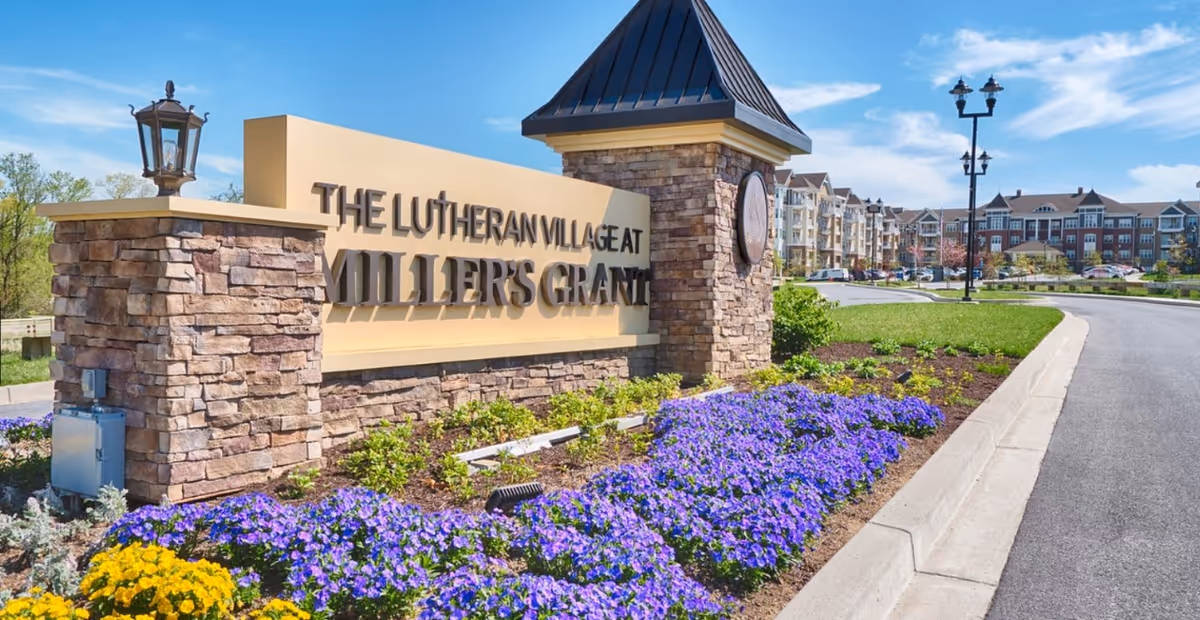Entrance sign for The Lutheran Village at Miller's Grant with stone pillars and flowers.