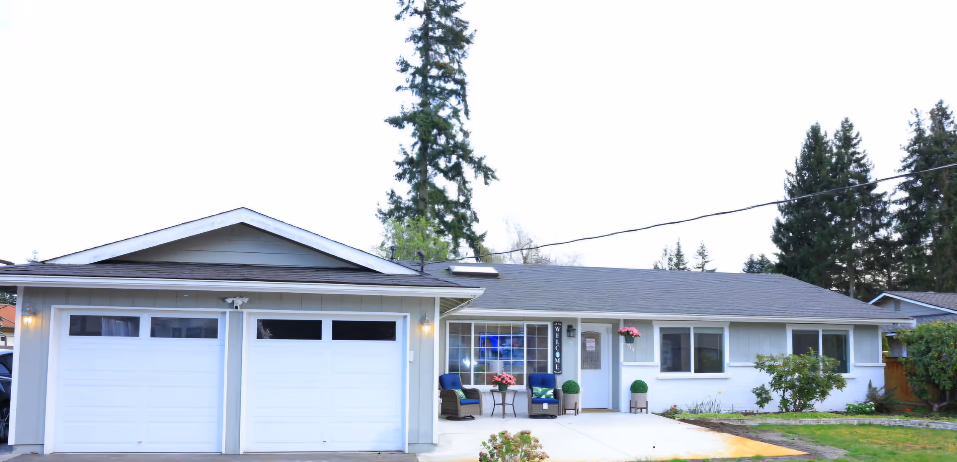 A single-story house with a two-car garage and front porch seating area.