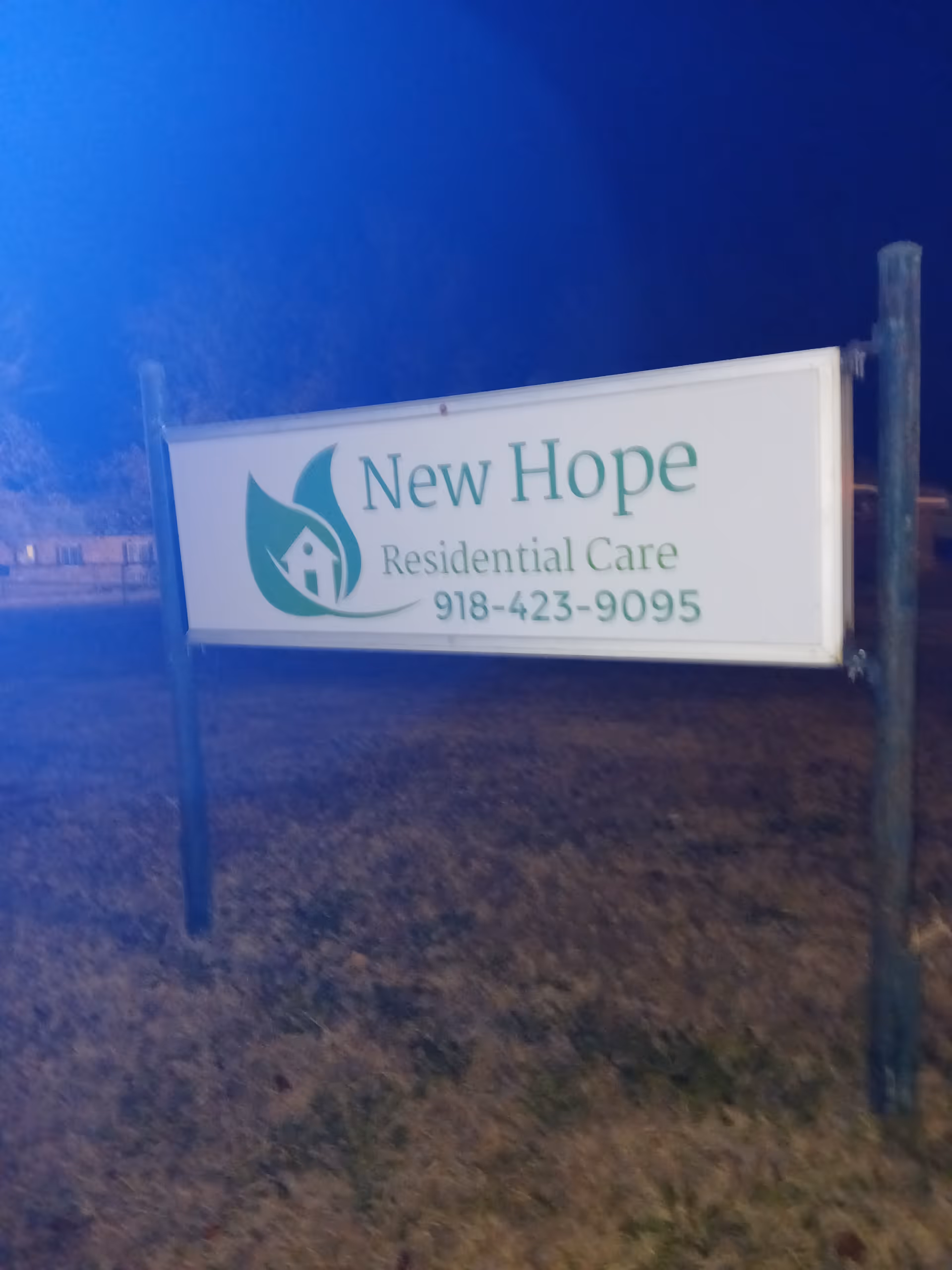 Outdoor New Hope Residential Care sign on two posts in a grassy area at dusk