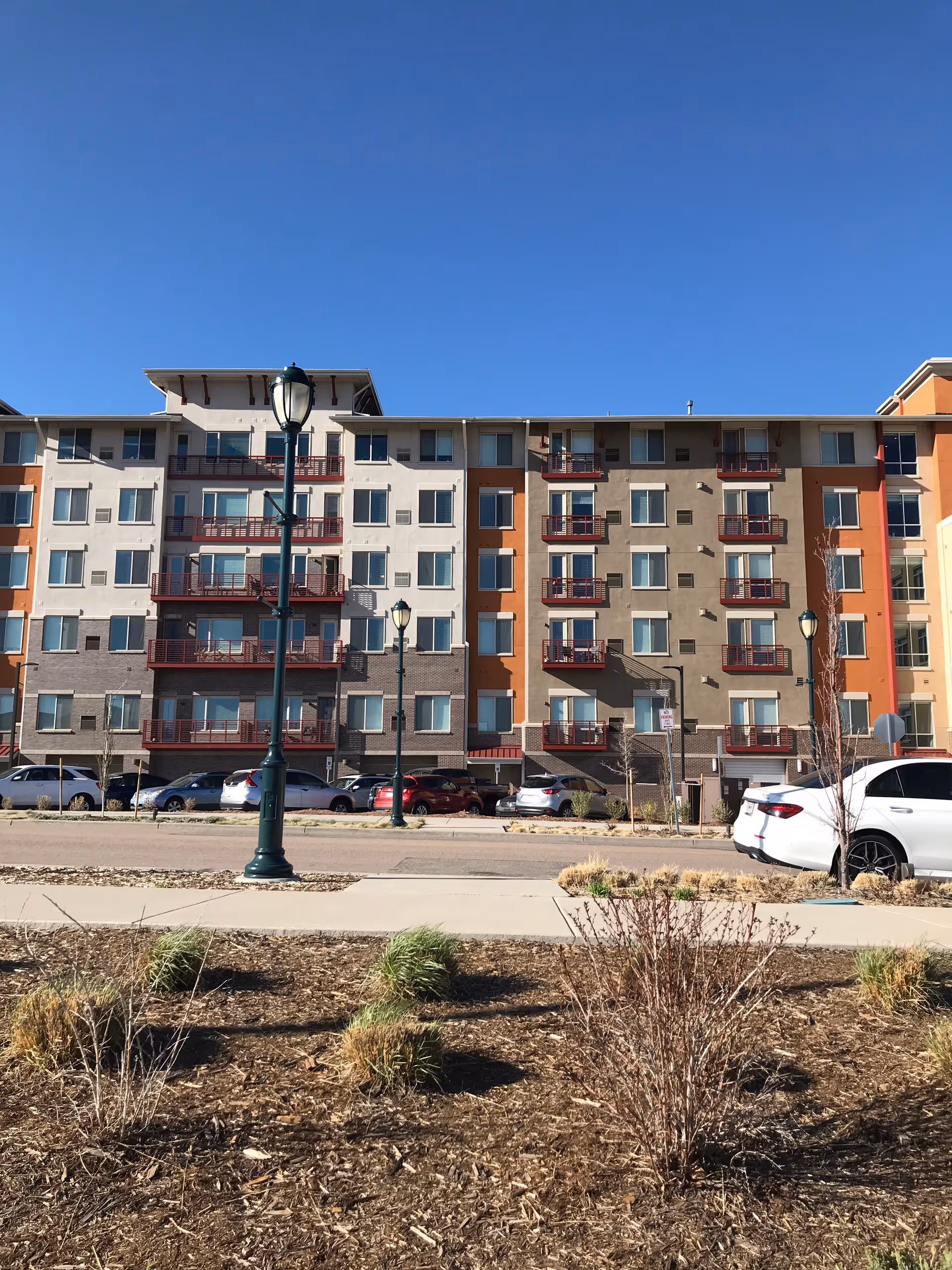 MorningStar Senior Living at RidgeGate building with balconies, parked cars, and clear blue sky.
