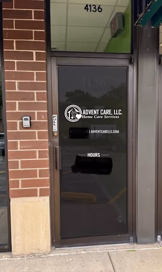Exterior door of Advent Care, LLC building with logo and brick wall.