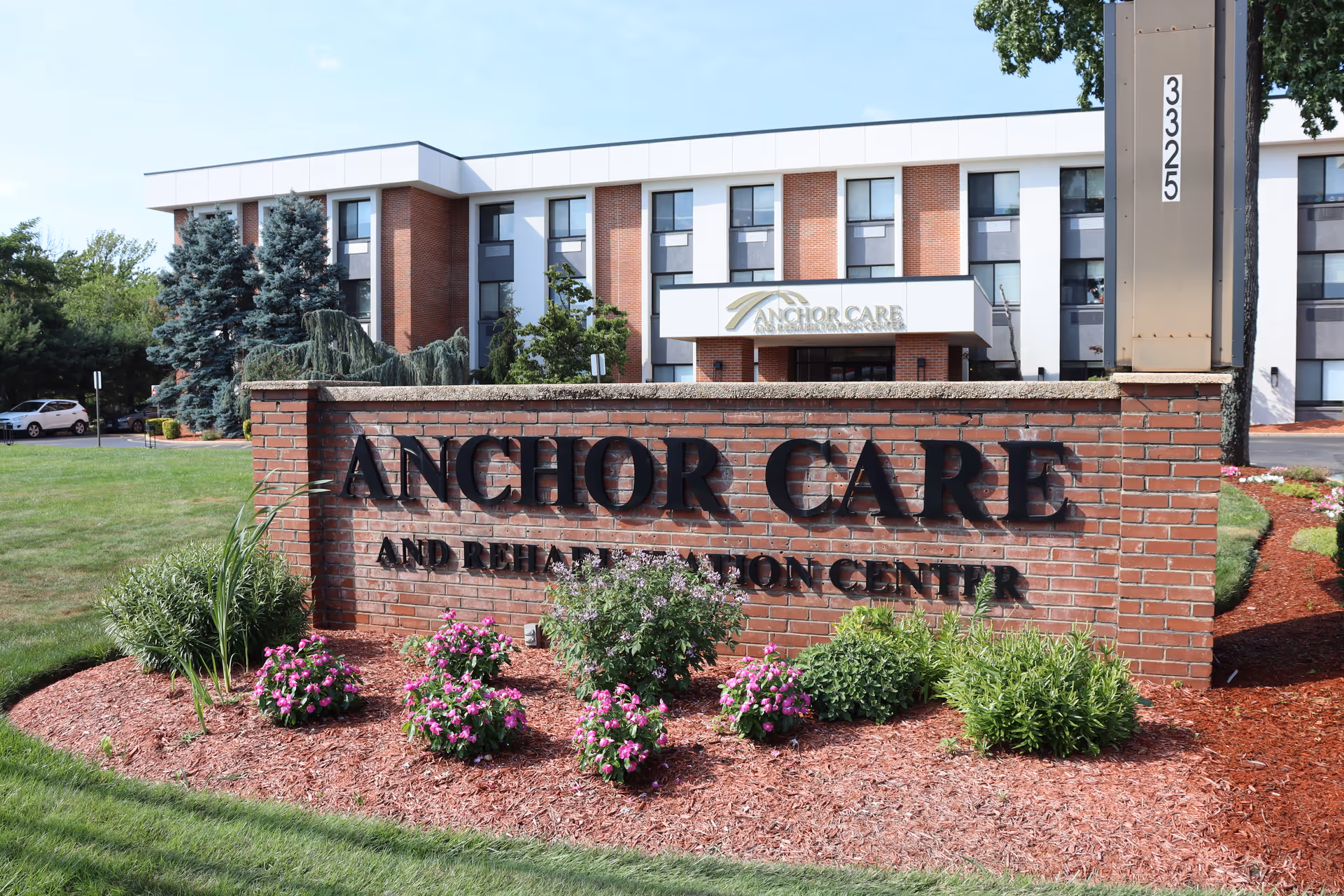 Exterior view of Anchor Care and Rehabilitation Center with brick sign and landscaped front.