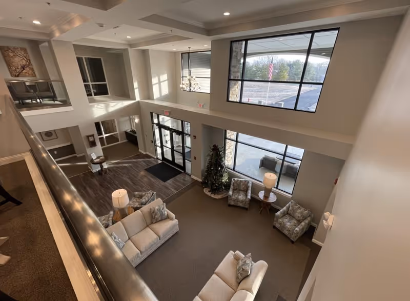 Senior living lobby with sectional sofas, chairs, large windows, and a Christmas tree
