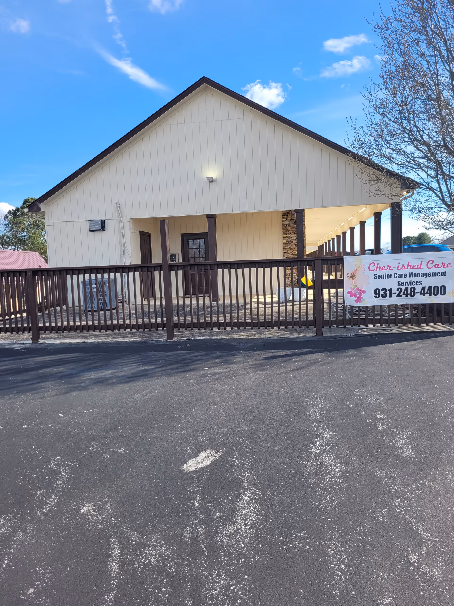 Front view of a light-colored building with a brown fence and banner.