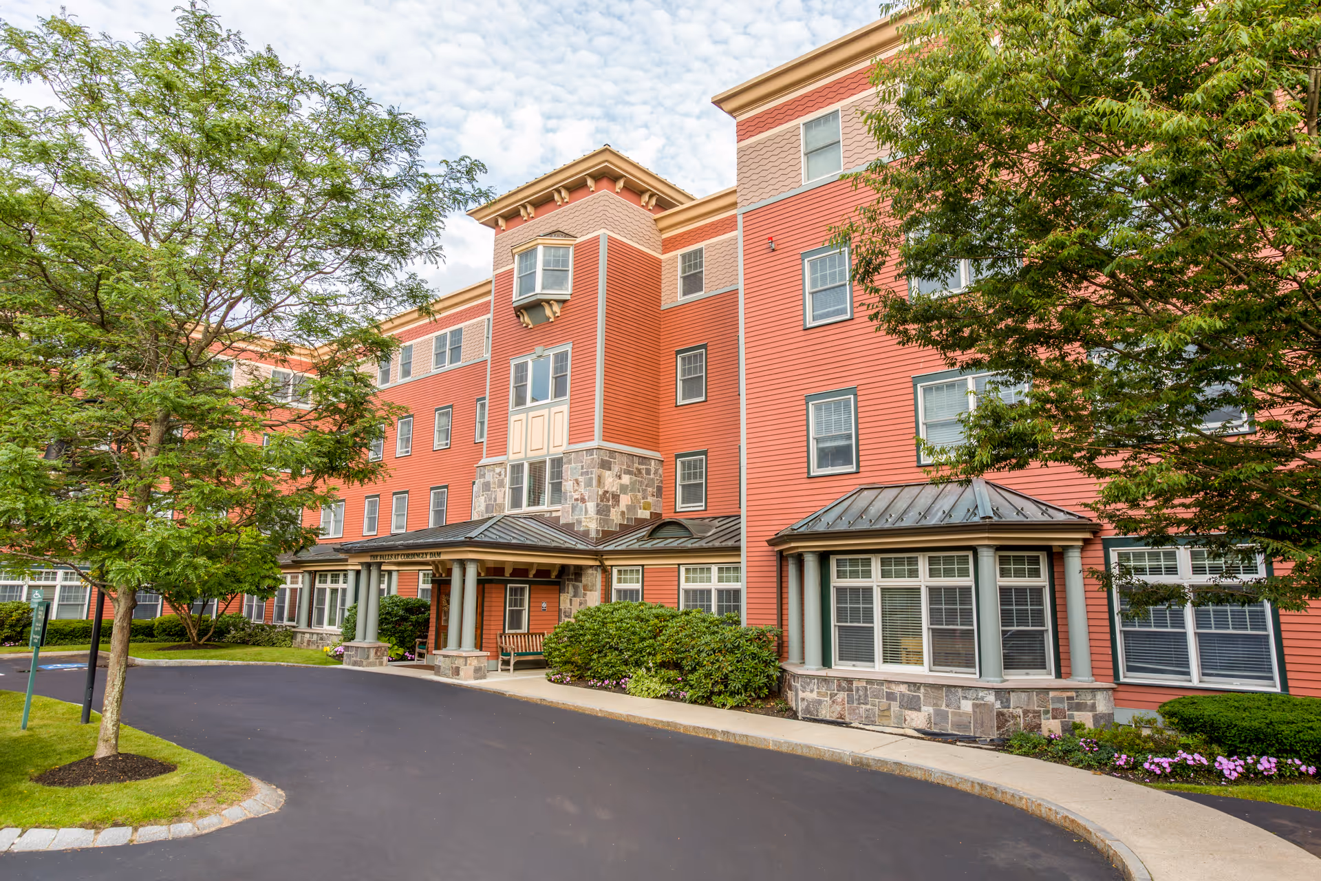 Exterior view of The Falls at Cordingly Dam, a red multi-story senior living building.