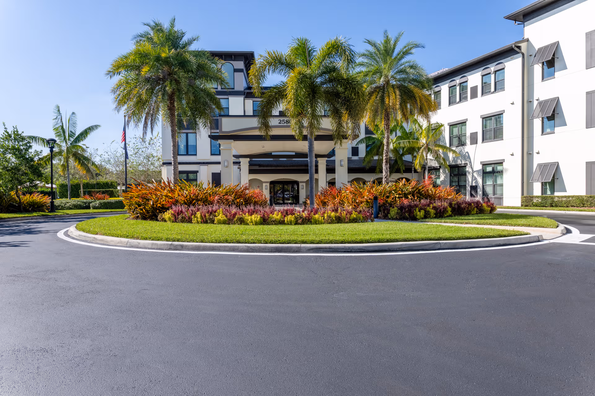 Exterior view of Arbor Terrace Cooper City with circular driveway, palm trees, and entrance.