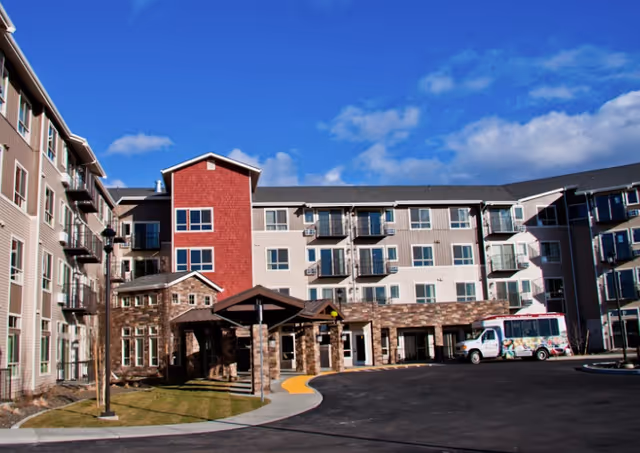 Exterior view of a modern multi-story senior living building with a main entrance.