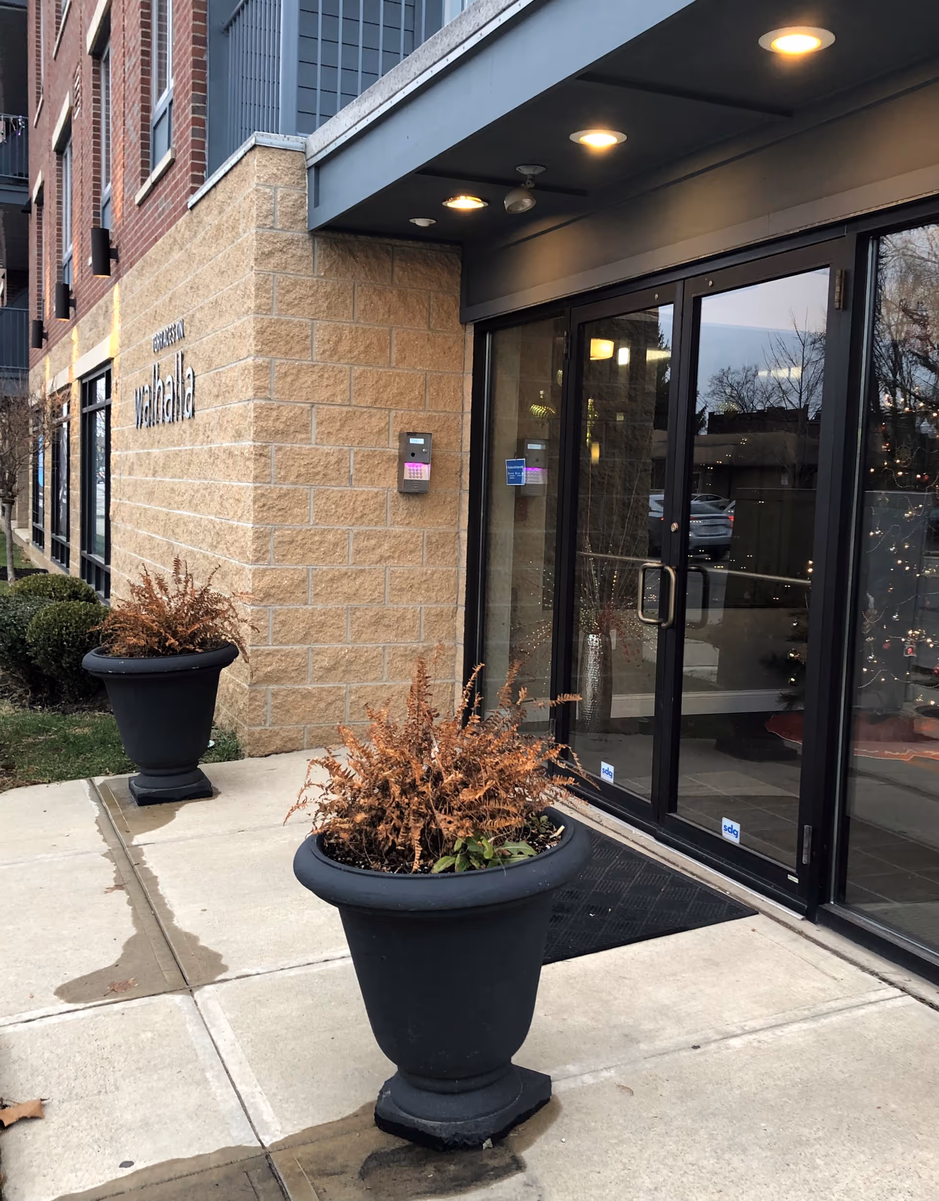 Exterior entrance of a senior care facility with glass doors and potted planters.