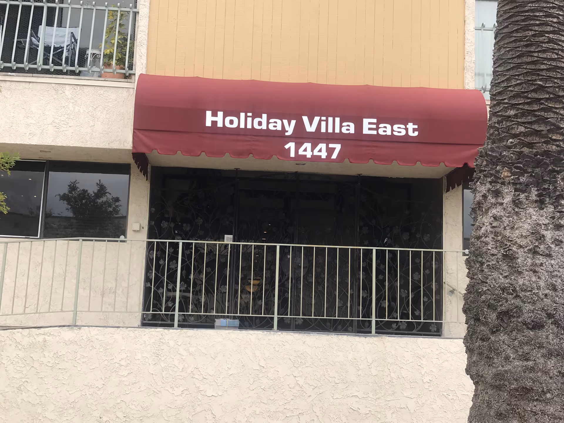 Front view of a building entrance with maroon awning reading Holiday Villa East
