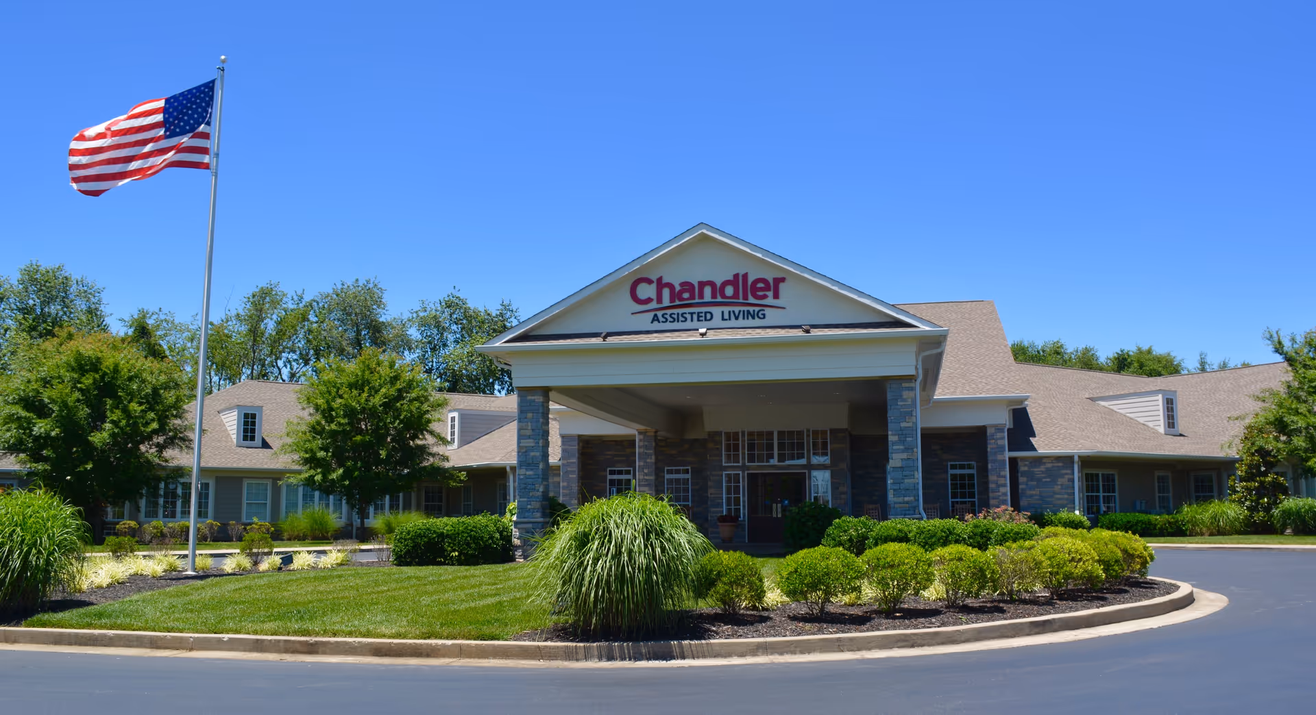 Exterior view of Chandler Park Assisted Living building with flagpole and manicured landscaping.