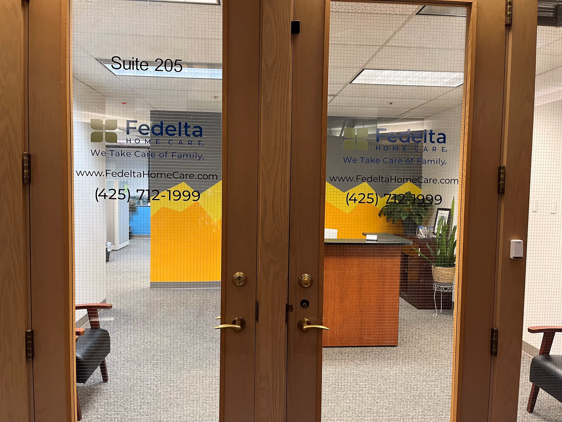Double glass doors show Fedelta Home Care signage and reception area inside Suite 205.