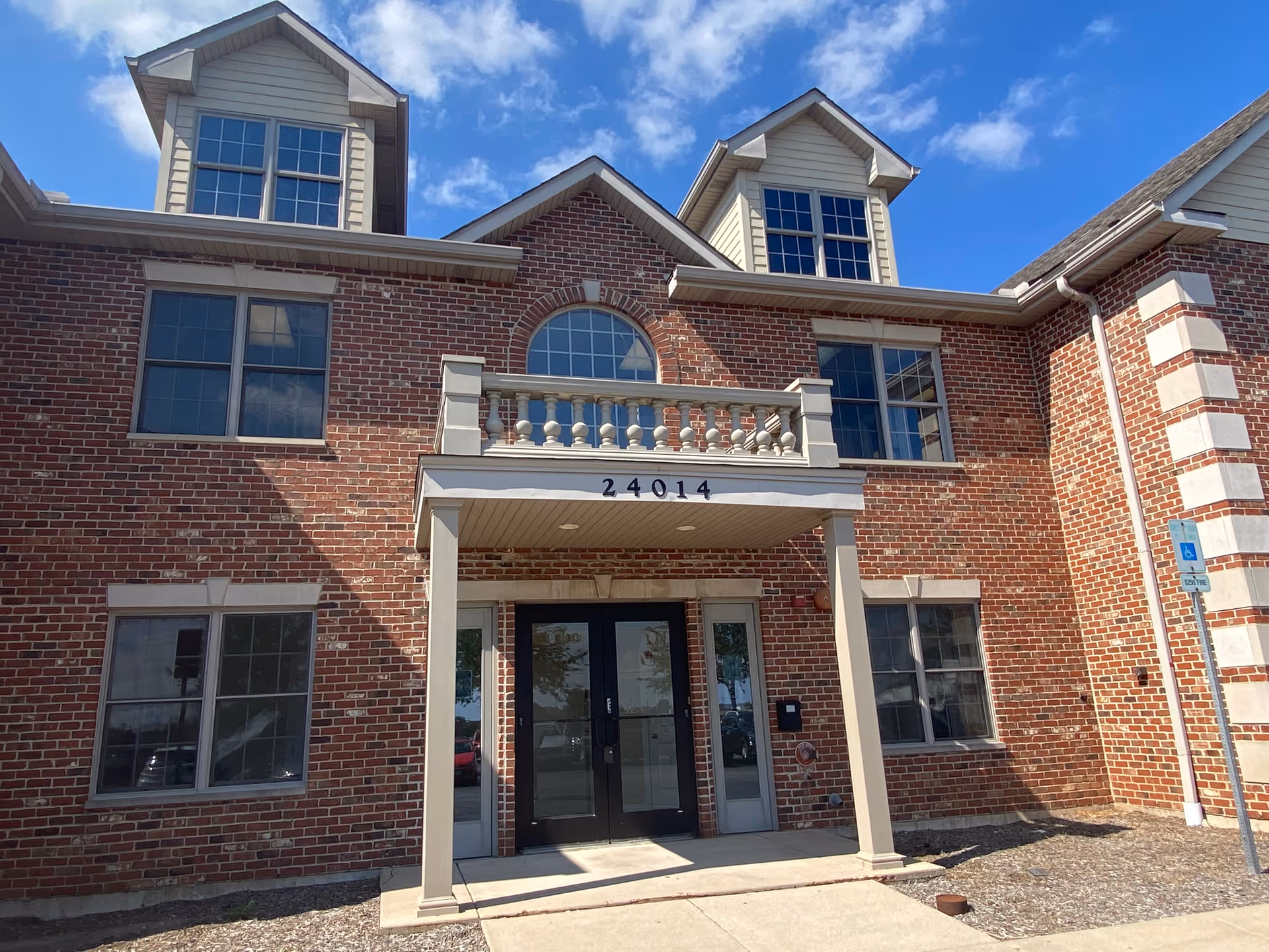 Brick senior living facility exterior with double doors and a small balcony.