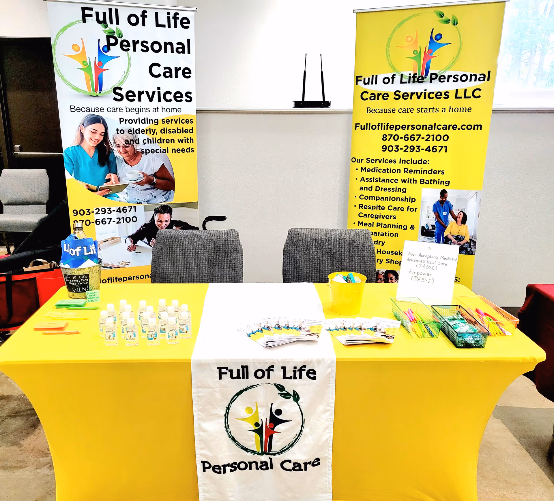 Indoor promotional booth with yellow banners and a table for Full of Life Personal Care.