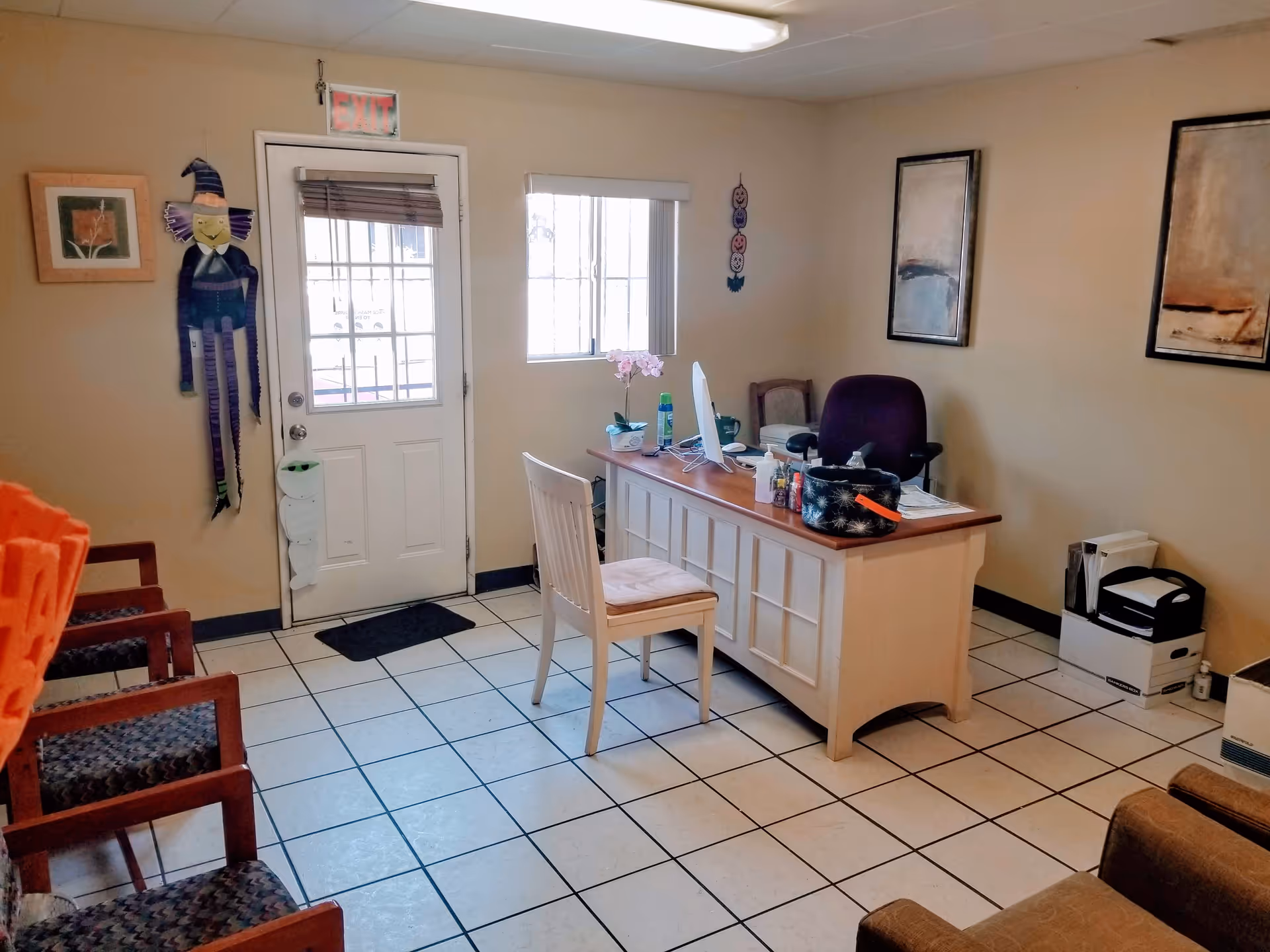 Reception area with front desk, chairs, door, window, and wall art in a senior facility