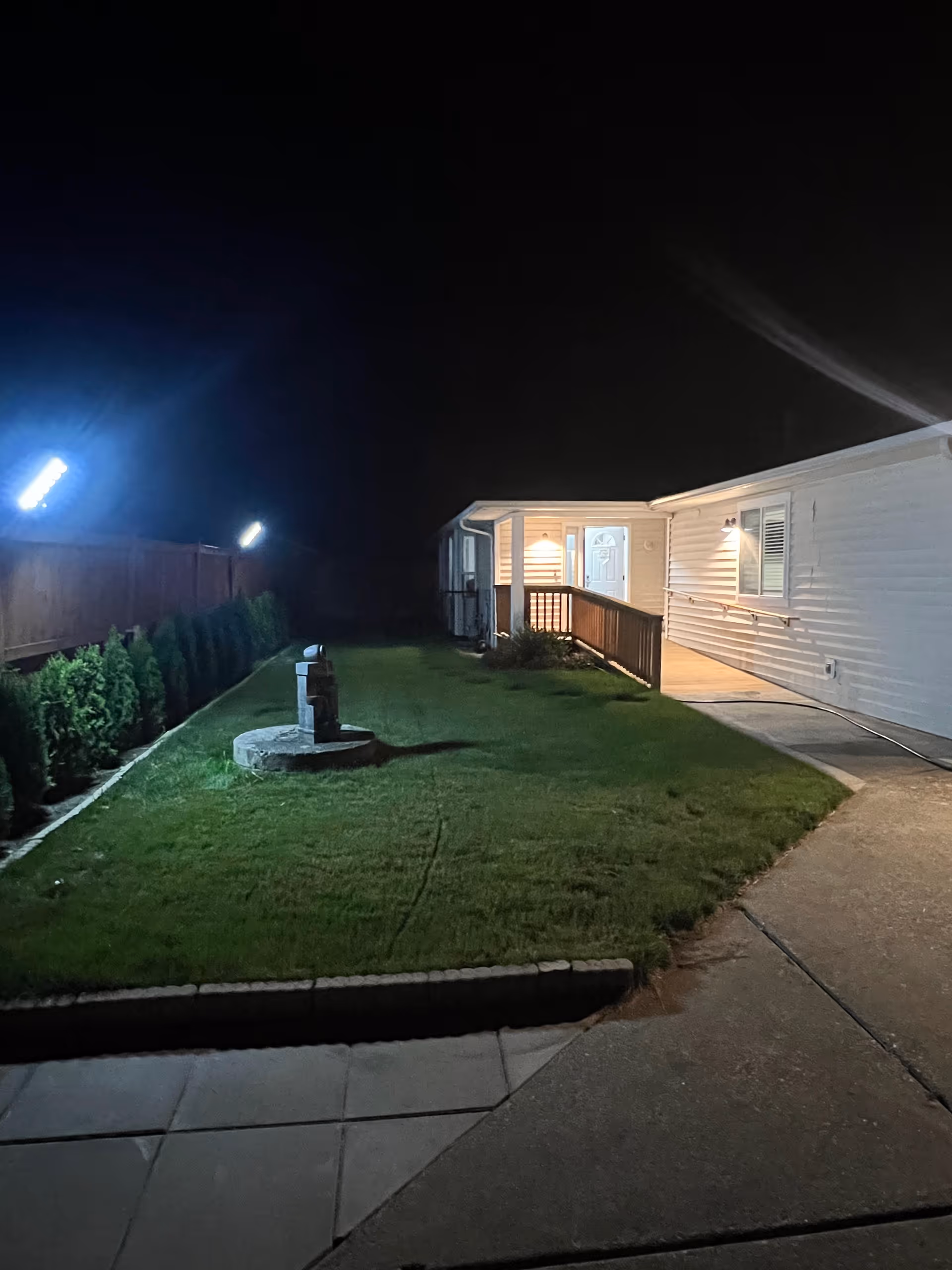 Night exterior of a senior living facility with lit entrance, fountain, and grassy front yard