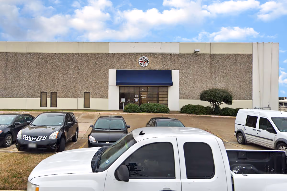 Front exterior of a medical facility with a blue awning entrance and parked cars.