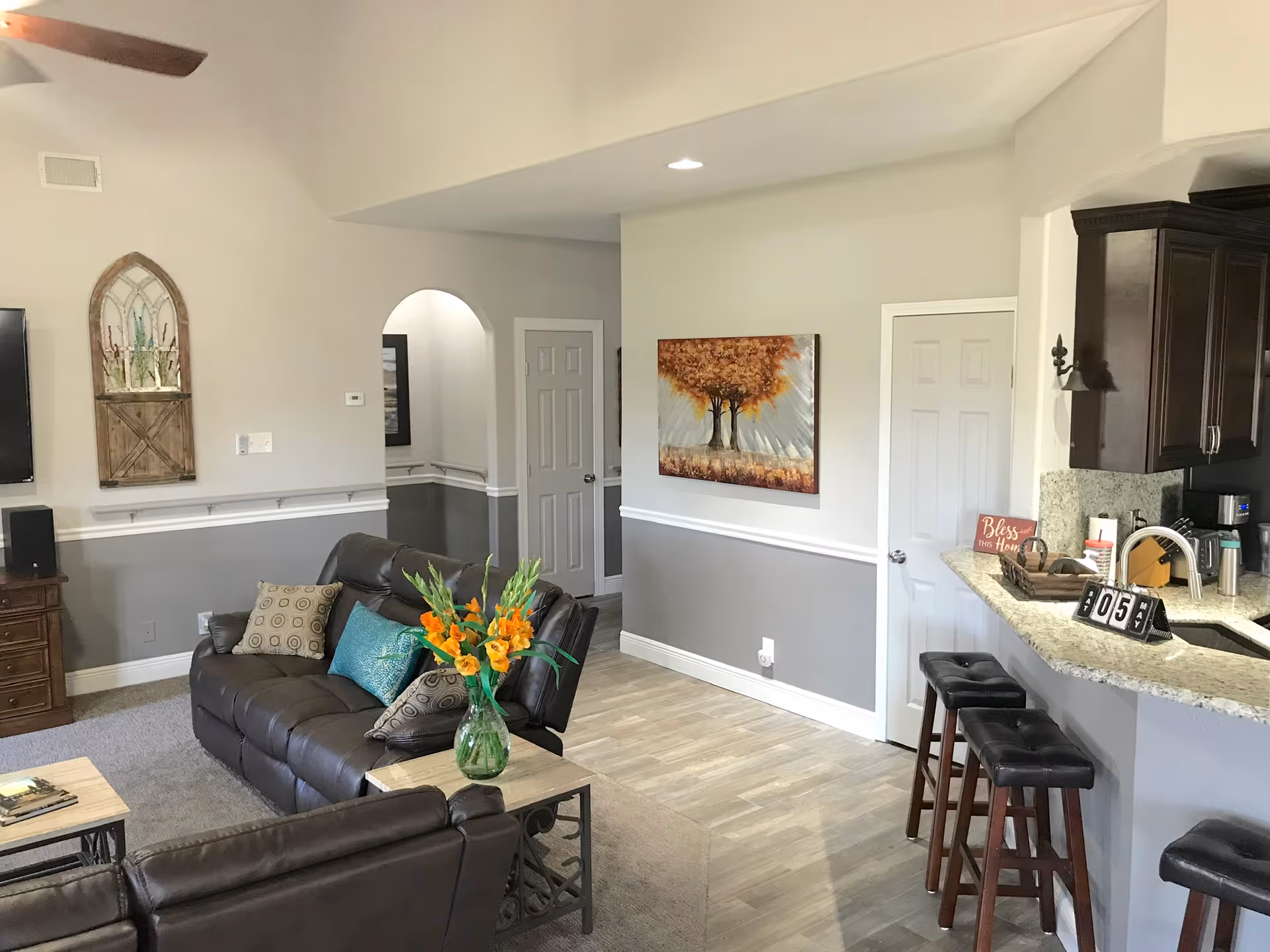 Open living area with leather sofa, kitchen counter with stools, and wall art.