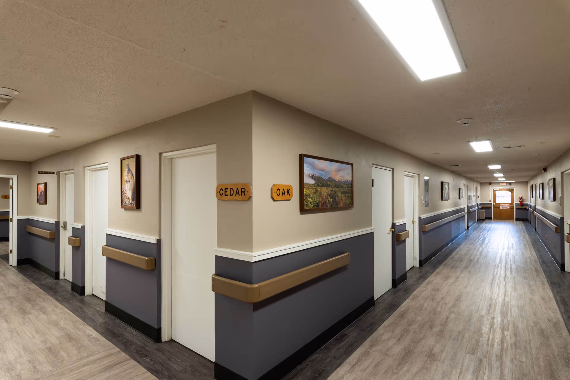 Long, well-lit interior corridor at Laramie Care Center with doors and wall art.