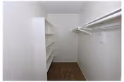 Empty walk-in closet with shelves on the left and hanging rods on the right.