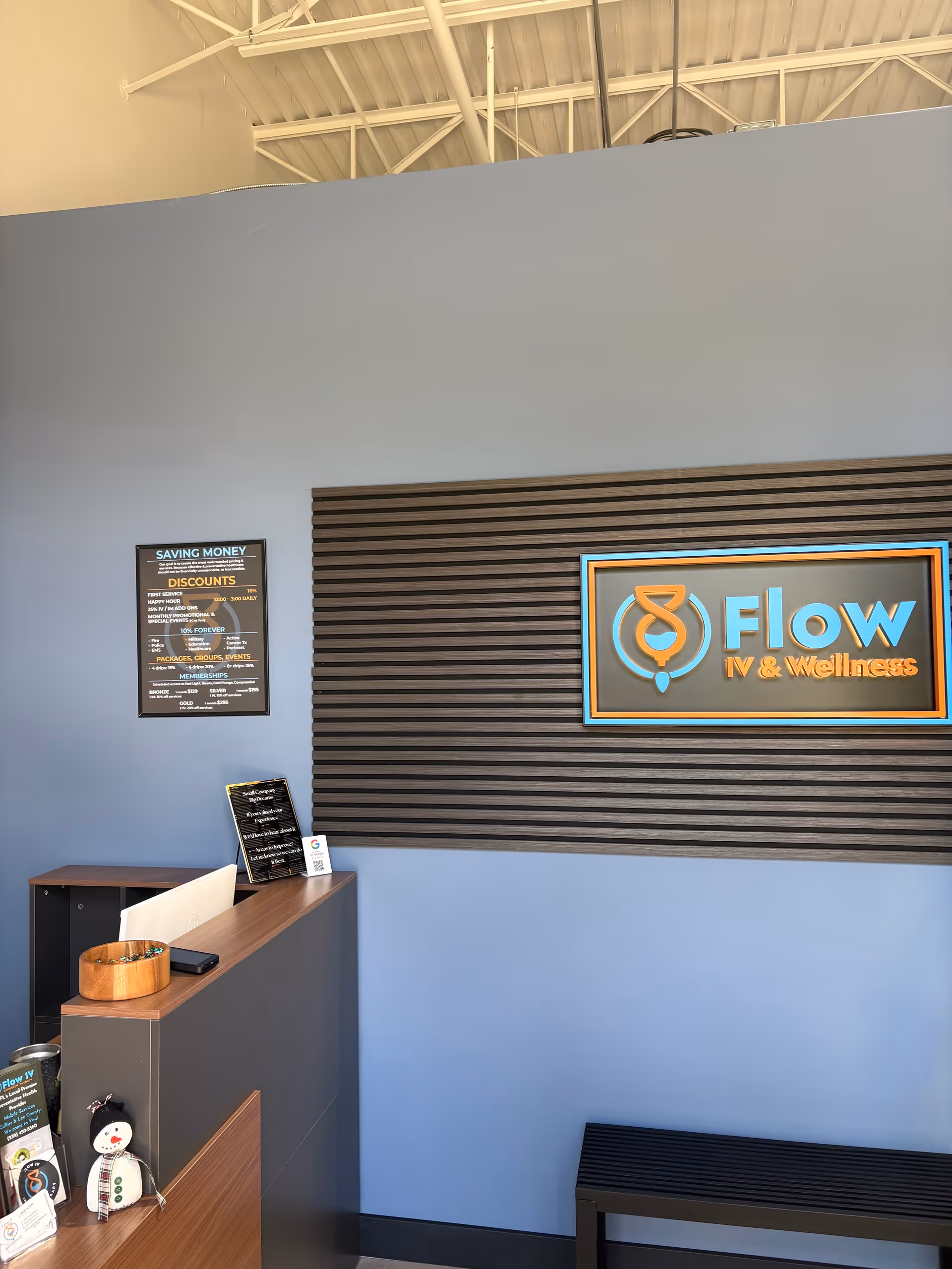 Reception area with Flow IV & Wellness Naples sign on blue wall and wooden desk.