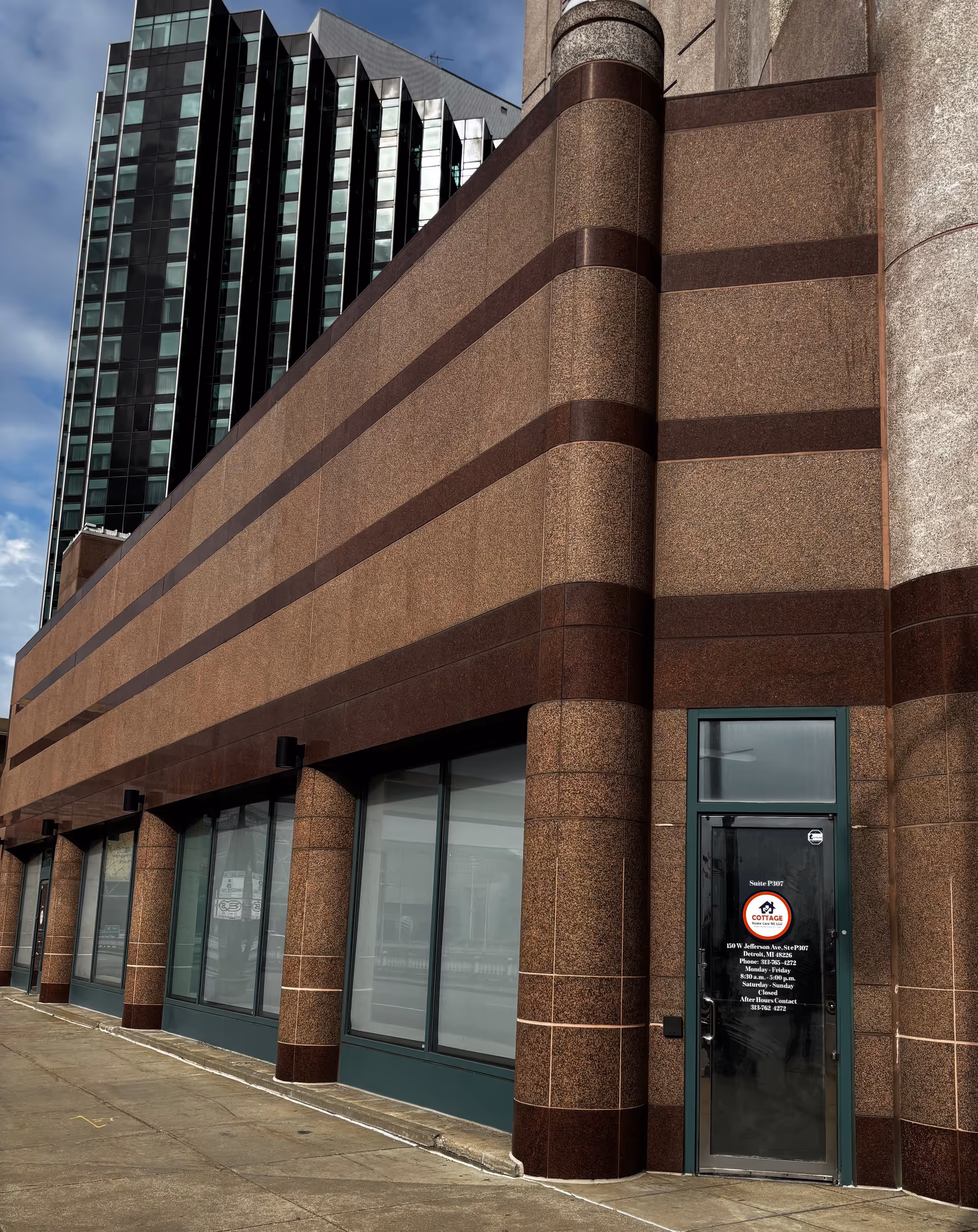 Modern brown brick building with tall glass windows and a Cottage Home Care MI door.