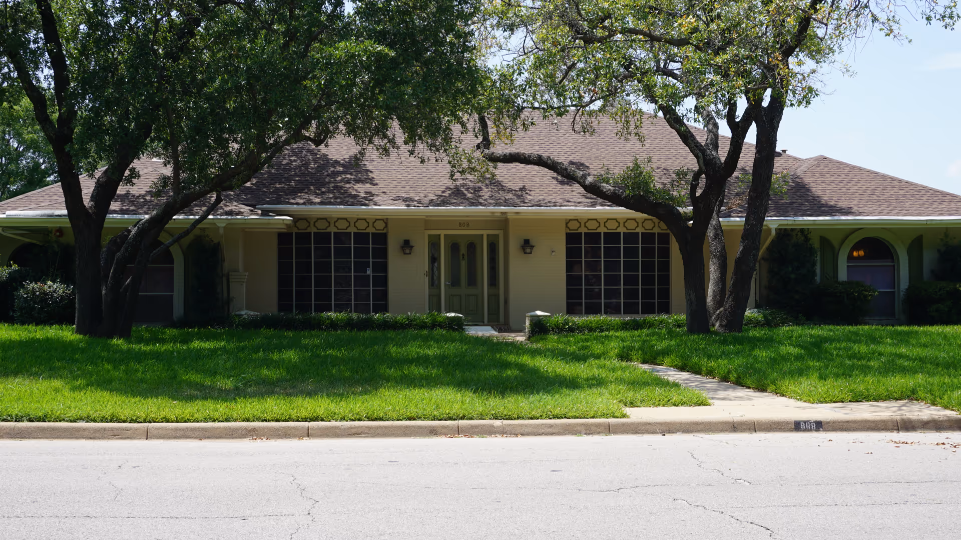 Front view of a single-story senior living facility with lawn and trees.