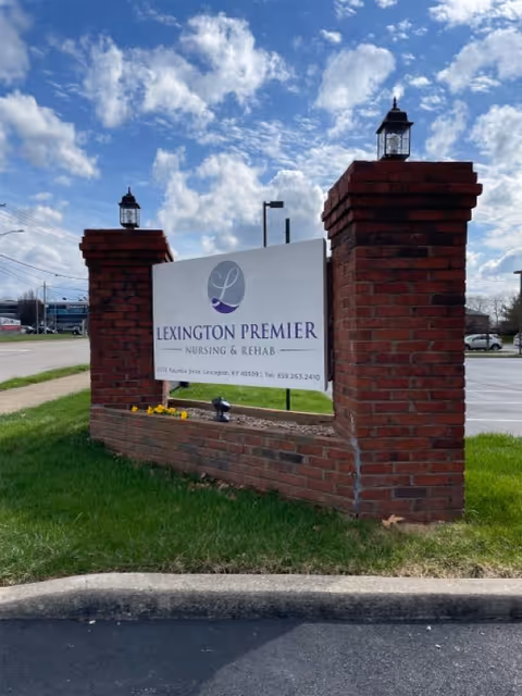 Front exterior sign for Lexington Premier Nursing and Rehab on brick pillars under a blue sky