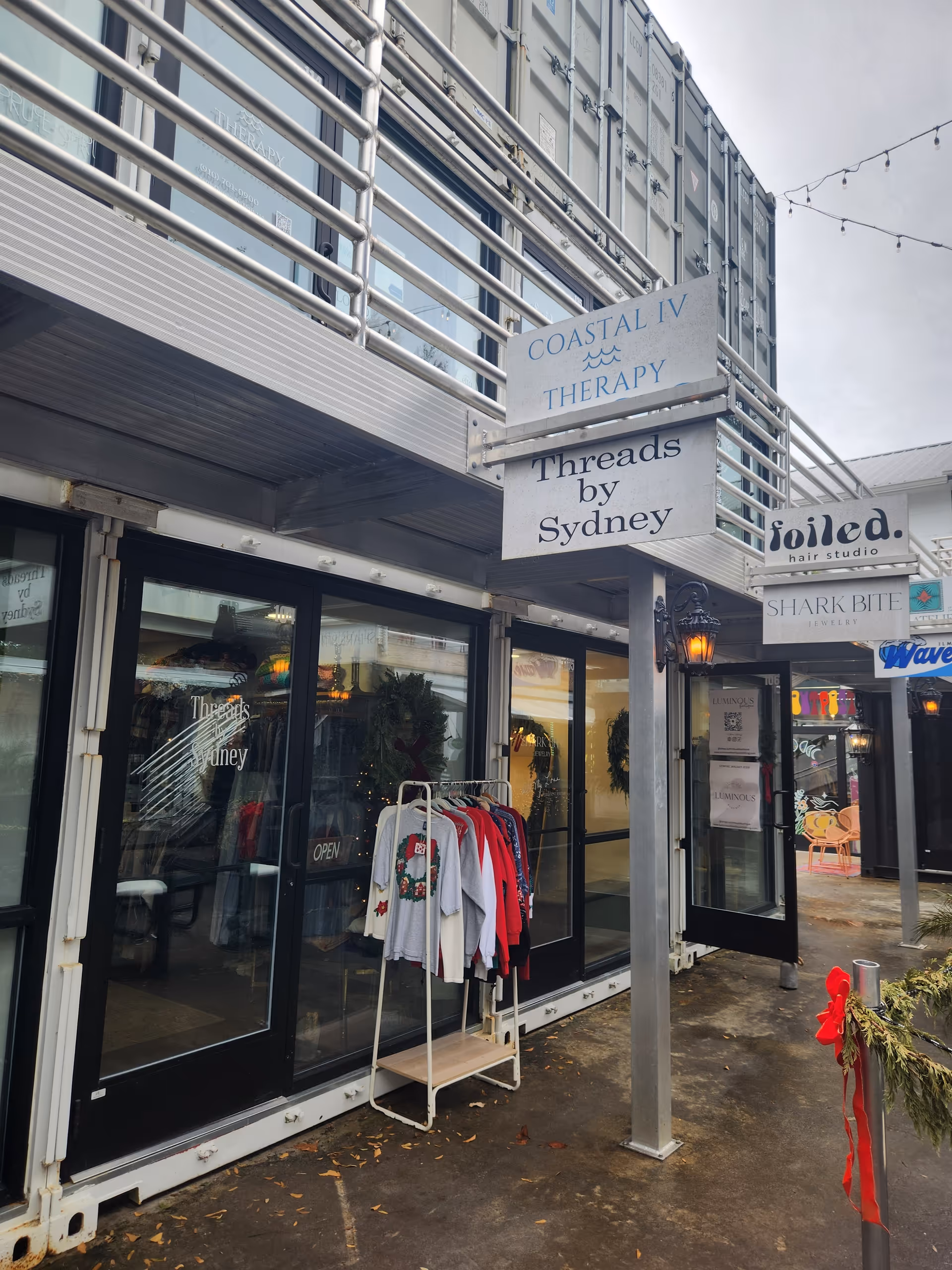Exterior storefronts with signs; clothing rack displayed outside a shop.