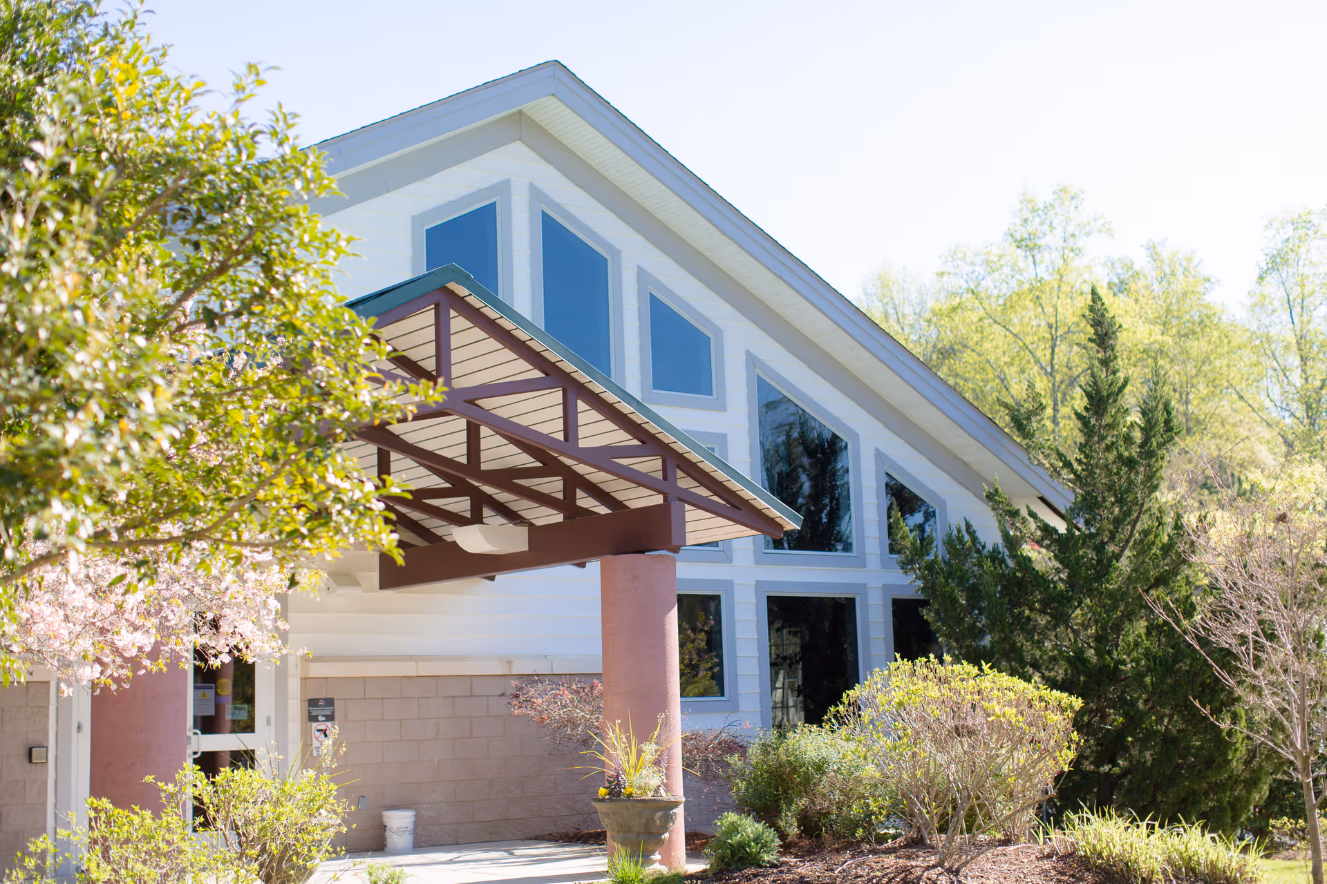 Exterior view of a Hospice of the Upstate building with large windows and surrounding greenery.
