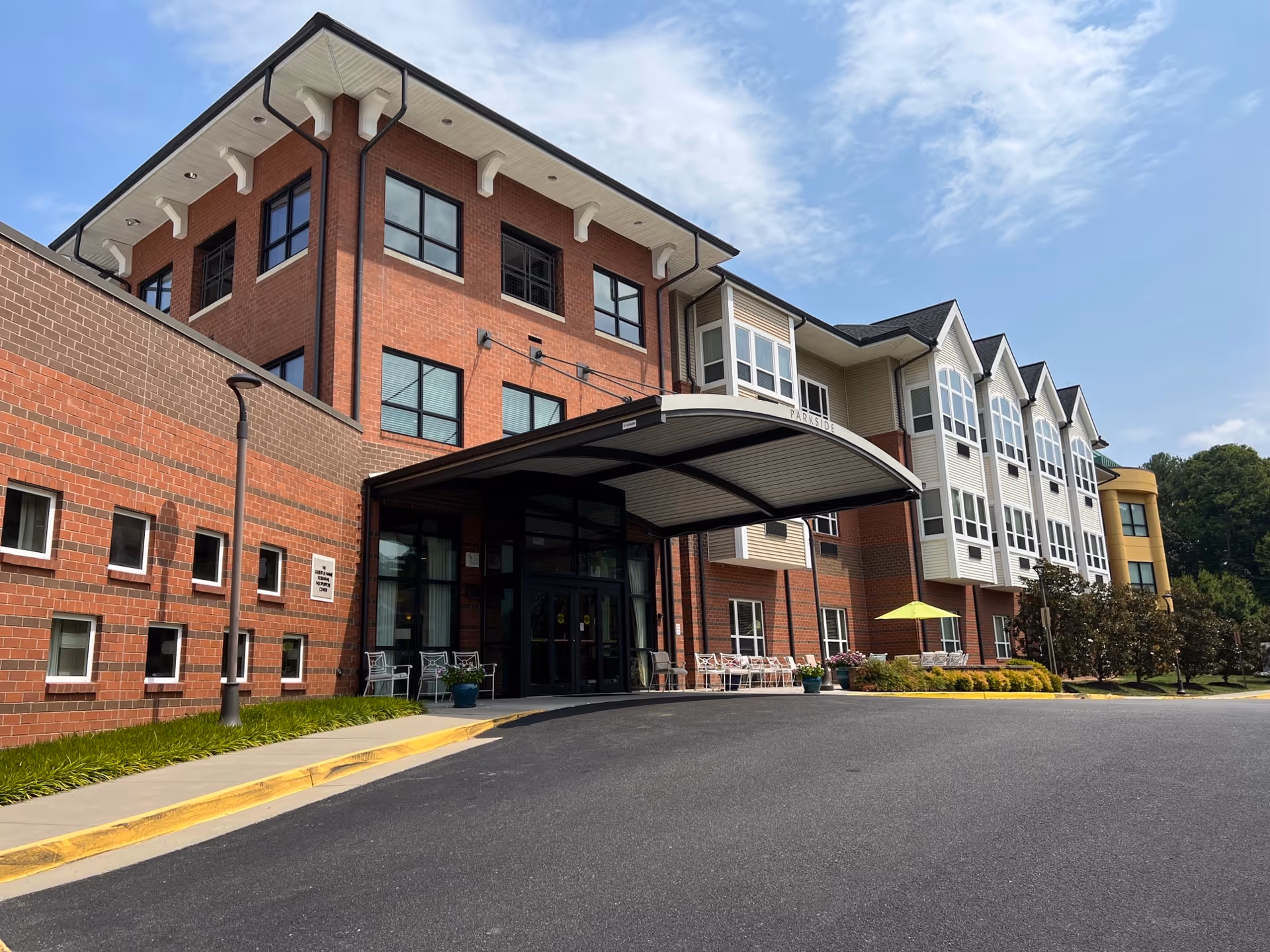 Exterior view of a brick senior living facility with a curved entrance canopy.