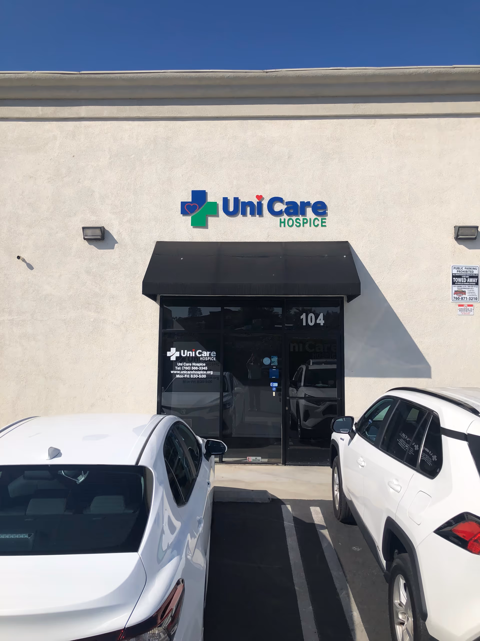 Front of Uni Care Hospice building with sign, entrance, and parked cars.