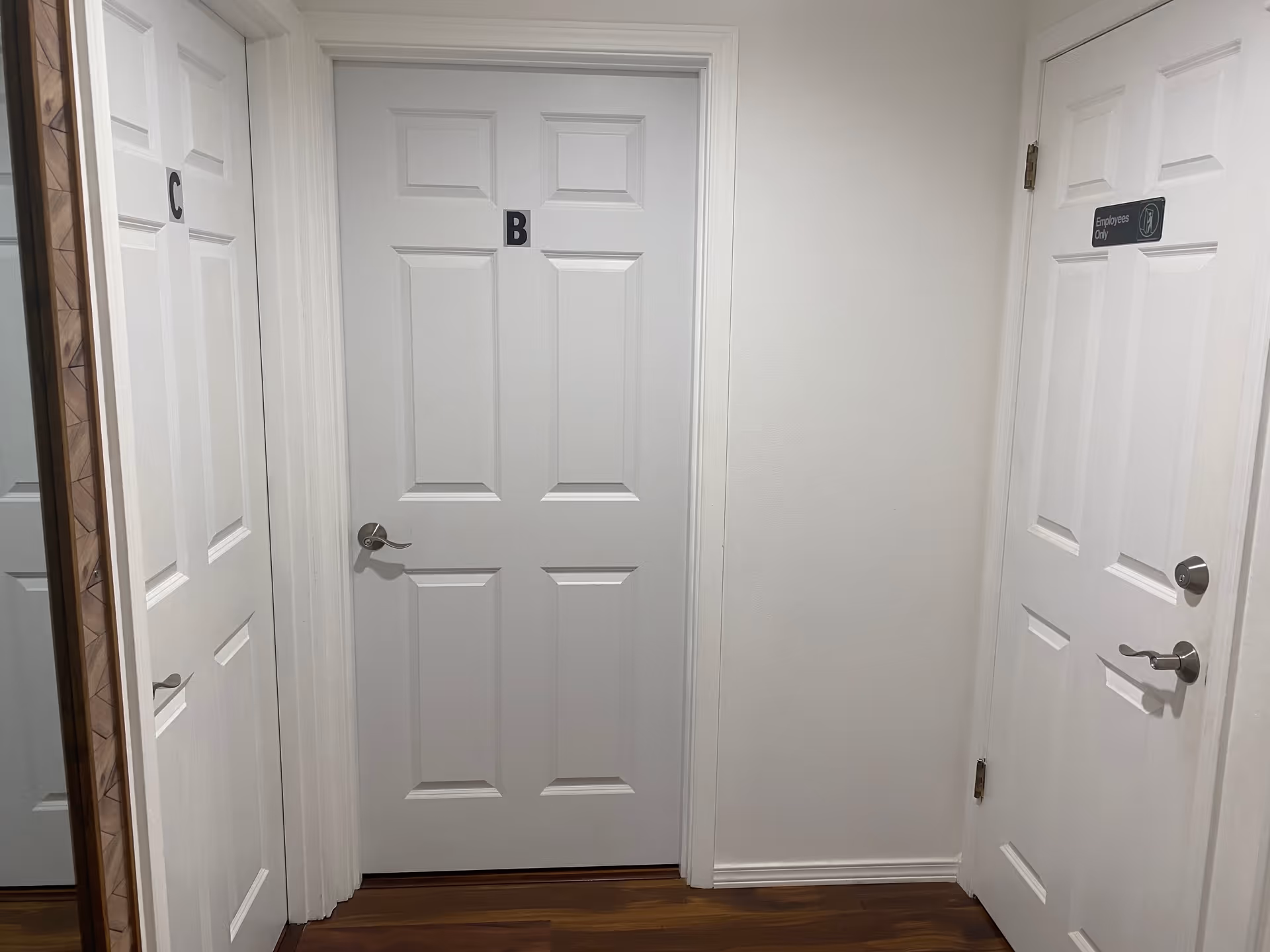 White hallway with multiple doors labeled B and C, including an Employees Only sign.